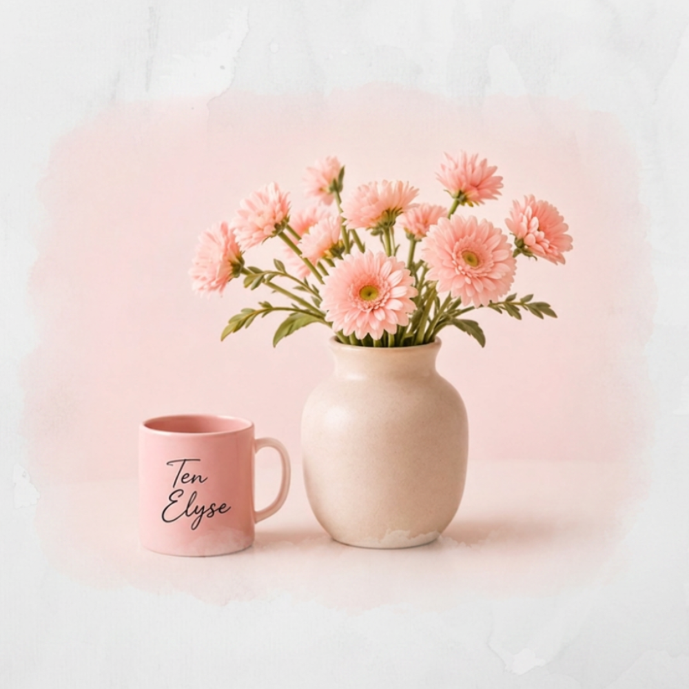 Pink roses in a cream vase beside a Ten Elyse mug