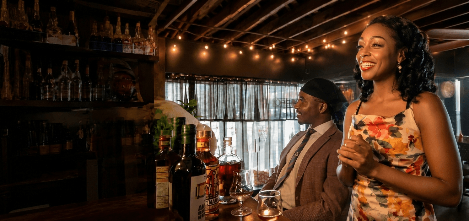 Ten Elyse at a warmly lit bar, mid-laugh, glass in hand